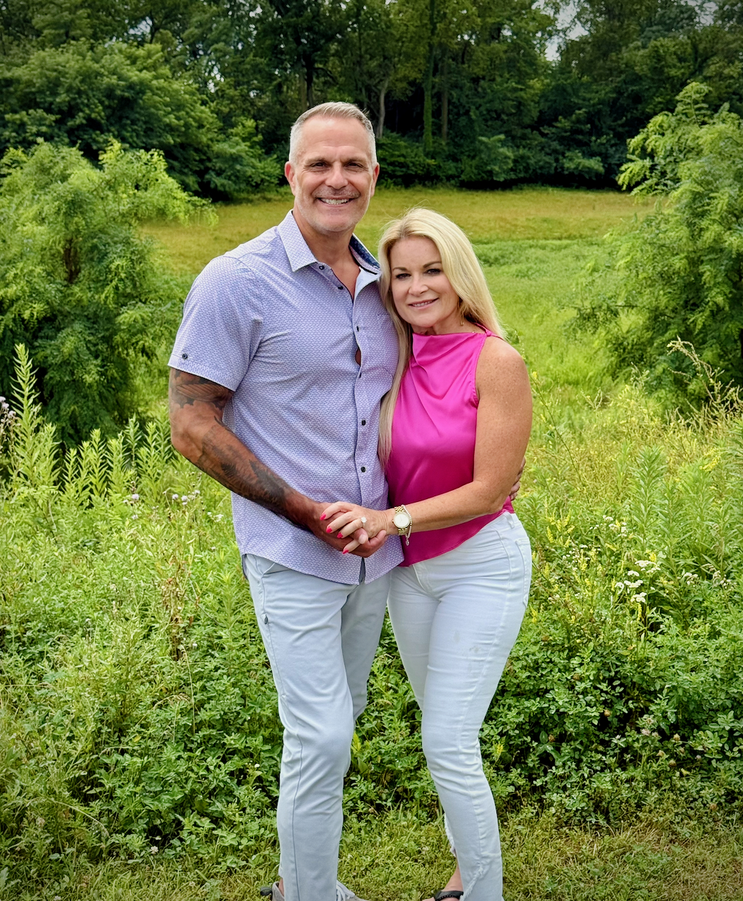 Ruby and DJ holding hands outdoors surrounded by greenery